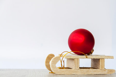 A wooden sled with a red Christmas ball on it. Preparing for the New year. Christmas card with a...