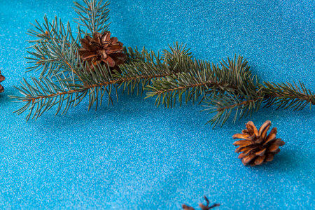 Layout of Christmas elements on a blue shiny background. Spruce branch and cones. Preparing for a happy Christmasの写真素材