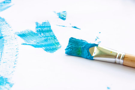 Smears of blue paint on white paper. The brush in the paint. Painted background.