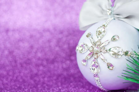 White Christmas ball in rhinestones for Christmas tree decoration. Christmas toy. Christmas toy for decorating a Christmas tree on a lilac background. Shining crystals on a white ball. Christmas and new year.の写真素材