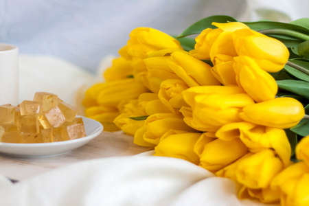 A bouquet of fresh yellow tulips and breakfast with coffee and homemade marmalade. Breakfast in bed. Spring flowers. The concept of spring and holiday, March 8, International Women's Day, birthday.の写真素材
