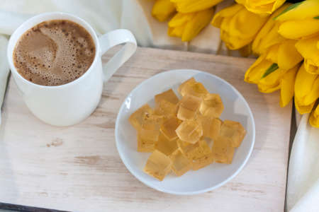 A bouquet of fresh yellow tulips and breakfast with coffee and homemade marmalade. Breakfast in bed. Spring flowers. The concept of spring and holiday, March 8, International Women's Day, birthday.の写真素材