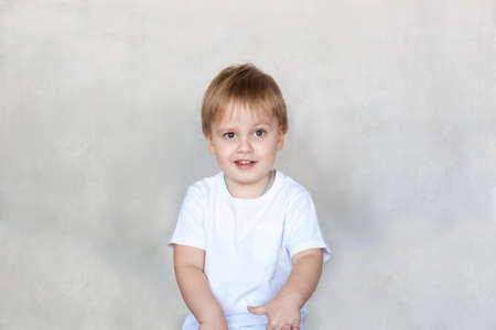 Portrait of a cute little boy in a white t-shirt. Children's emotions. Child on the background of the wall. Success, bright idea, creative ideas and concepts. The concept of an advertising banner.の写真素材