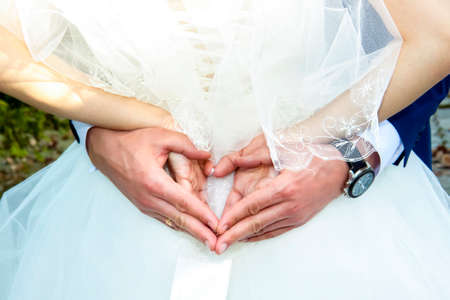 Hands of the newlyweds close-up. They folded the figure out of their hands behind their backs. Newlyweds, wedding.の写真素材