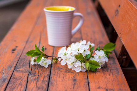 a cup of coffee on a dark, worn rustic wooden table. The composition is decorated with a twig with...