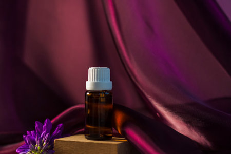 Bottle without label with oil on the stand. Transparent glass container with a dispenser on a beige-pink background. Product banner. Space for text, design. Cosmetology and the concept of beautyの写真素材