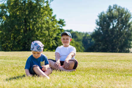 Cheerful children, two brothers, smile with joy. we are happy to walk and play on the lawn in warm sunny weather in the park. the emotions of children on the face. Happinessの写真素材