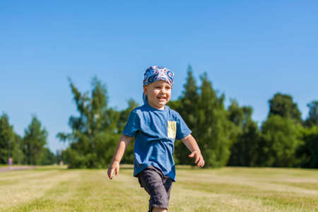 Portrait of a boy, smiling with joy. I am happy to walk in the park in warm sunny weather. the emotions of the child on the face.の写真素材