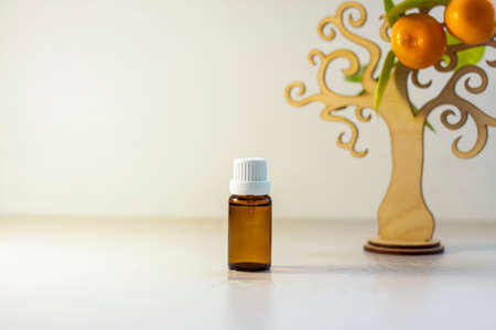 A bottle without a label with tangerine oil. Transparent glass bottle of brown color. A natural cosmetic product. Product banner. A place for text and design. Cosmetology and the concept of beautyの写真素材
