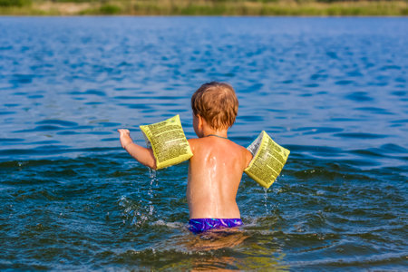 A happy child is swimming in the river on a very hot summer day. Swim in reservoirs. A happy family has fun and splashes in the water in the summer. Family on vacationの写真素材