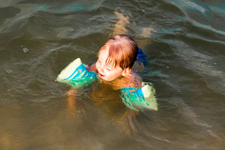 A happy child is swimming in the river on a very hot summer day. Swim in reservoirs. A happy family has fun and splashes in the water in the summer. Family on vacationの写真素材