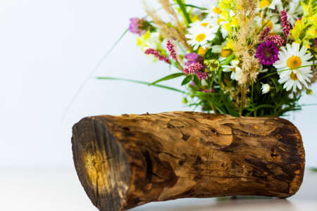 a dry stump, tree bark and a bouquet of wild flowers in a small glass vase. Stylish appearance, layout, personality. Banner, a place for the text. Background for advertising and presentation.の写真素材