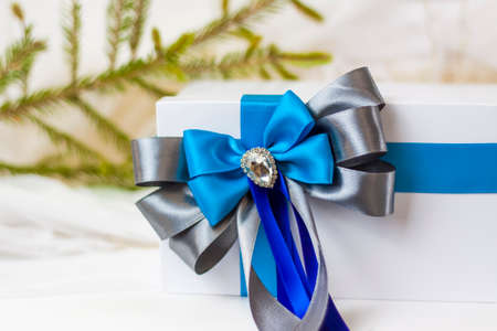 A Christmas gift decorated with a beautiful bow on a light background with a twig, if. Selective focus. the concept of Christmas and New Year. background for the banner.の写真素材