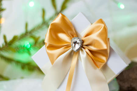A Christmas gift decorated with a beautiful bow on a light background with a twig, if. Selective focus. the concept of Christmas and New Year. background for the banner.の写真素材