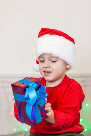 Portrait of a cute boy in a Santa Claus hat. Funny smiling child. Gifts, toys, joy, celebration. Christmas concert.の写真素材