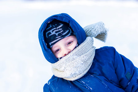A smiling happy child lies in a snowdrift on a sunny winter day. A lot of snow and very frosty....