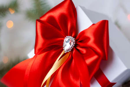 A Christmas gift decorated with a beautiful bow on a light background with a fir twig. Gifts, joy, surprise. Selective focus. the concept of Christmas and New Year. background for the banner.の写真素材