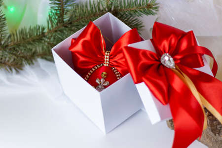 A Christmas gift decorated with a beautiful bow on a light background with a fir twig. Gifts, joy, surprise. Selective focus. the concept of Christmas and New Year. background for the banner.の写真素材