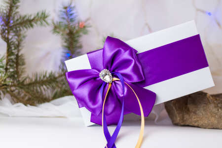 A Christmas gift decorated with a beautiful bow on a light background with a fir twig. Gifts, joy, surprise. Selective focus. the concept of Christmas and New Year. background for the banner.の写真素材