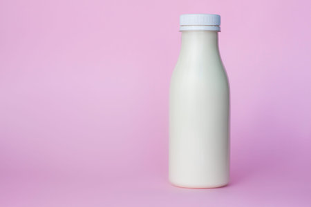 A bottle of white milk, highlighted on a pink background, close-up. Dairy product concept, copy...