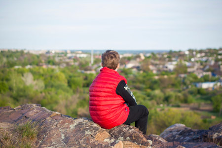 A child sits on top of a cliff and watches what is happening below. panoramic view from the top of a rocky mountain. Russia, Rostov region, skelevataya skala, the 7th wonder of the Don world. Landscapeの写真素材
