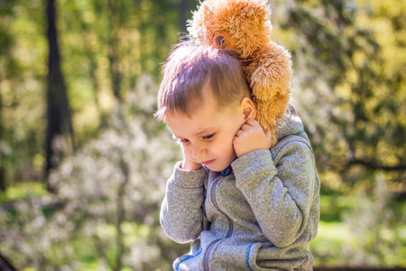 A cute boy is playing with a bear cub in the forest. The sun's rays envelop the space of the clearing with a stump. A magical story of interactions for the book. Space for copying. selective focus.の写真素材