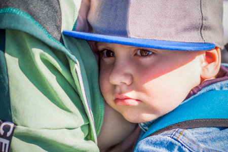 A moody child cuddles up to his young grandmother in the park. The woman feels sorry for the boy in her arms. interactions. selective focus. Springの写真素材