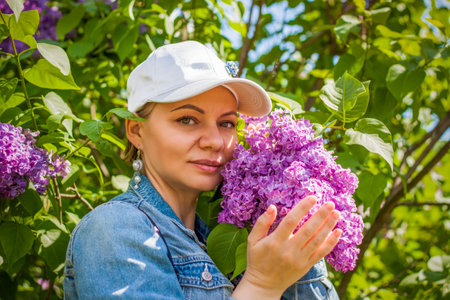 A young woman in a white cap poses near a lilac bush. portrait of a girl. interactions. selective focus. Springの写真素材