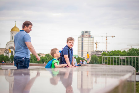 Portrait of a child, a boy against the backdrop of urban landscapes of skyscrapers and high-rise buildings in the open air. children, travel. Lifestyle in the city. Center, streets. Summer, a walk.の写真素材
