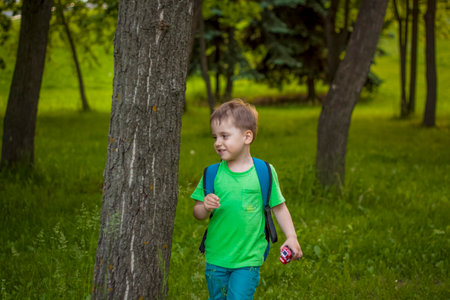 Portrait of a child, a boy against the background of plants in an open-air park. children, travel. Lifestyle in the city. Center, streets. Summer, a walk.の写真素材