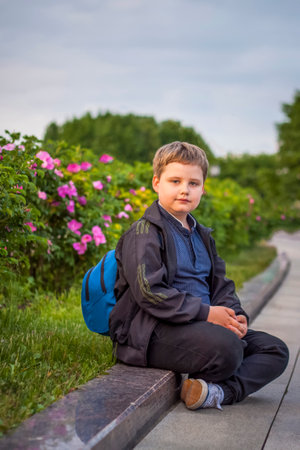 Portrait of a child, a boy against the background of plants in an open-air park. children, travel. Lifestyle in the city. Center, streets. Summer, a walk.の写真素材
