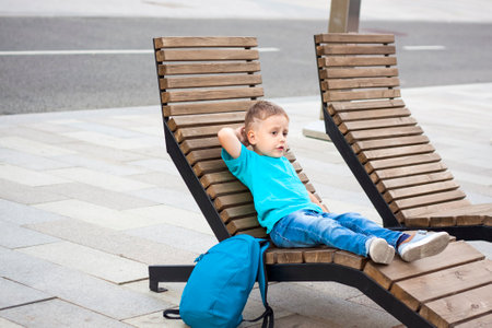 A boy in a blue T-shirt is resting on a chaise longue that stands on the embankment. Journey. The face expresses natural joyful emotions. Not staged photos from nature.の写真素材