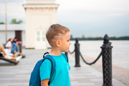 A boy in a blue T-shirt with a backpack on his back. Journey. The face expresses natural joyful emotions. Not staged photos from nature.の写真素材