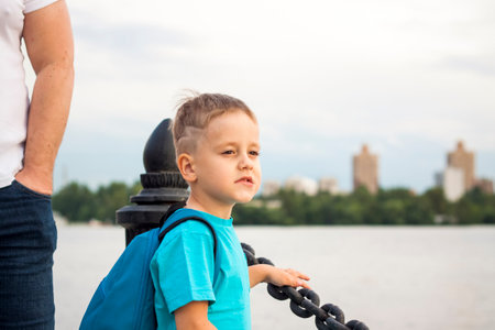 A boy in a blue T-shirt with a backpack on his back. Journey. The face expresses natural joyful emotions. Not staged photos from nature.の写真素材