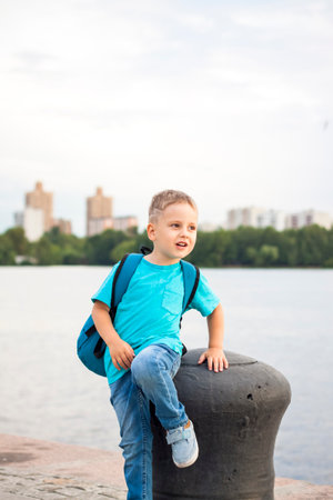 A boy in a blue T-shirt with a backpack on his back. Journey. The face expresses natural joyful emotions. Not staged photos from nature.の写真素材