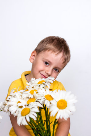 A cute boy with a beautiful bouquet of large daisies. Portrait of a child, funny and cute facial expression. selective focus. A postcard for the celebration of the day of family, love and fidelity.の写真素材
