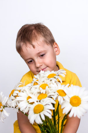 A cute boy with a beautiful bouquet of large daisies. Portrait of a child, funny and cute facial expression. selective focus. A postcard for the celebration of the day of family, love and fidelity.の写真素材