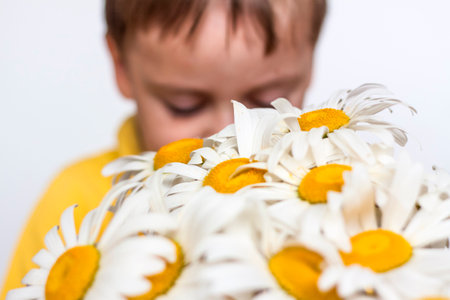 A cute boy with a beautiful bouquet of large daisies. Portrait of a child, funny and cute facial expression. selective focus. A postcard for the celebration of the day of family, love and fidelity.の写真素材