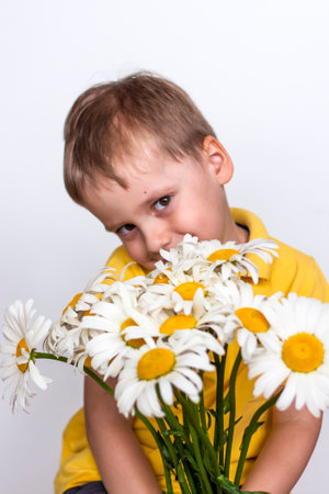 A cute boy with a beautiful bouquet of large daisies. Portrait of a child, funny and cute facial expression. selective focus. A postcard for the celebration of the day of family, love and fidelity.の写真素材