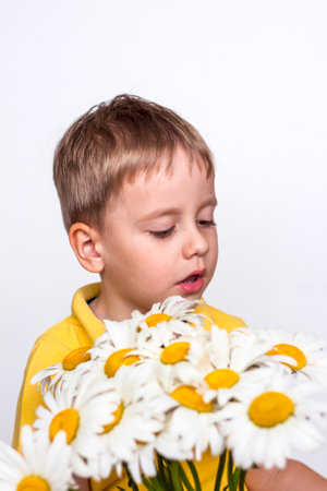 A cute boy with a beautiful bouquet of large daisies. Portrait of a child, funny and cute facial expression. selective focus. A postcard for the celebration of the day of family, love and fidelity.の写真素材