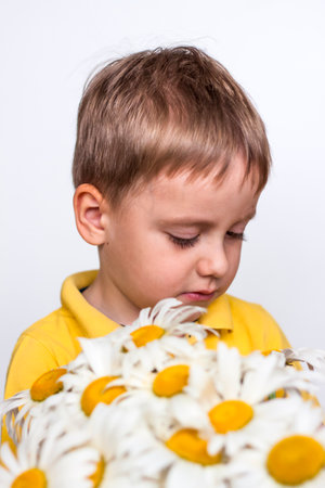 A cute boy with a beautiful bouquet of large daisies. Portrait of a child, funny and cute facial expression. selective focus. A postcard for the celebration of the day of family, love and fidelity.の写真素材