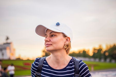 Portrait of a girl in a cap on the background of an open-air urban landscape. Travel. Lifestyle in the city. Center, streets. Summer, a walk.の写真素材
