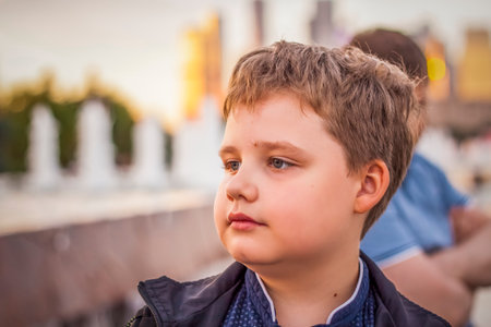 Portrait of a child, a boy against the backdrop of urban landscapes of skyscrapers and high-rise buildings in the open air. children, travel. Lifestyle in the city. Center, streets. Summer, a walk.の写真素材
