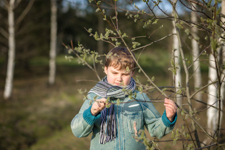 A funny boy walks through the spring park, examines the leaves with a large magnifying glass, looks for bugs and enjoys. A happy child. Portraitの写真素材