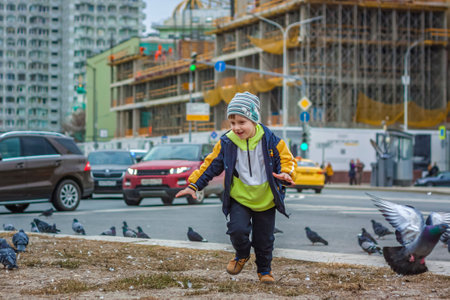 2023-04-09. Moscow, Russia. A boy is hunting and trying to catch street pigeons in Moscow. Birds, pigeons, chaseのeditorial素材