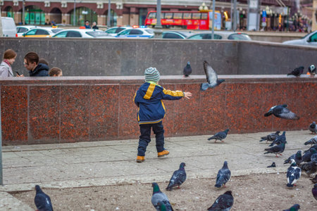 2023-04-09. Moscow, Russia. A boy is hunting and trying to catch street pigeons in Moscow. Birds, pigeons, chaseのeditorial素材
