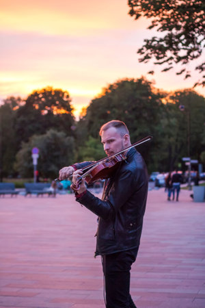 2022-07-17. Russia. Moscow. Northern River Station. A musician plays the violin on the street near the train station.のeditorial素材