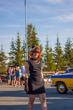2022-08-12 Tatarstan, Verkhneuslonsky district, Savino village. Resort town "Sviyazhsky hills". Kazan Festival of Historical Cars. A man and a woman in retro clothes pose near carsのeditorial素材