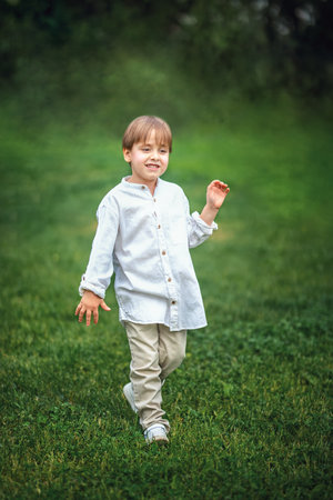 A young handsome boy of European appearance enjoys spending time on the green lawn at home. It's a great time to relax. Portrait of a child.の写真素材