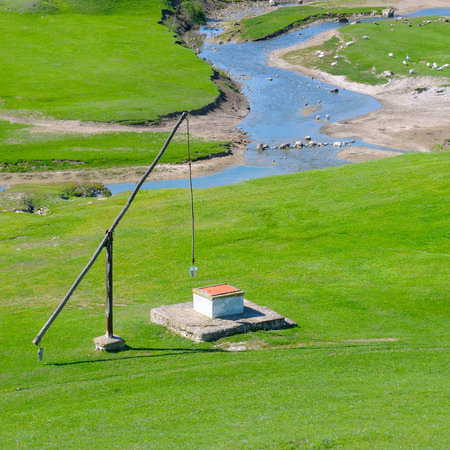 Green meadow, river and well Craneの写真素材